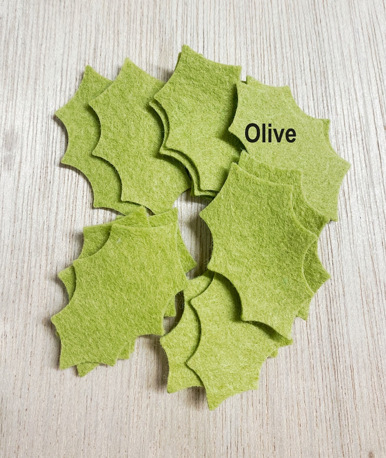 Może przedstawiać: Stosik oliwkowych zielonych gwiazdek z filcu. Na jednej z gwiazdek napisano "Olive".