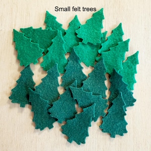 May include: A collection of small, felt Christmas trees in varying shades of green. The trees are arranged in a scattered pattern, with the text "Small felt trees" at the top. These decorative trees are ideal for crafting and holiday decor.