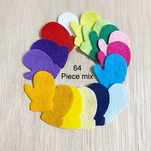 May include: A set of 64 felt mitten shapes in various colors, including red, blue, yellow, green, purple, and white. The mittens are arranged in a circle on a wooden surface. "64 Piece mix" is written in black text on a white background.