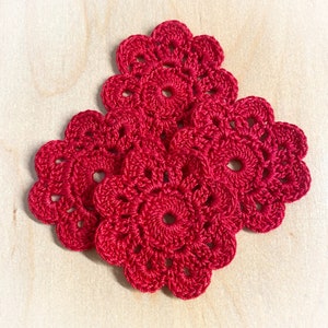 May include: Three red crocheted doilies with a flower design.