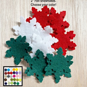 May include: A pile of felt snowflakes in red, white, and green. The snowflakes are 2 inches in diameter. The text "2" Felt snowflakes. Choose your color!" is visible in the image.