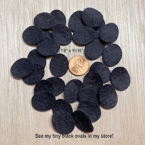 May include: A collection of small, black oval felt shapes, approximately 7/8" x 11/16", are scattered on a light wood-grain surface. A penny is included for size comparison. The text "See my tiny black ovals in my store!" is at the bottom.