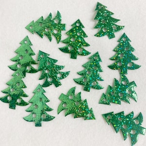May include: Twelve green glitter Christmas tree ornaments with a sparkly finish. The ornaments are various sizes and shapes.