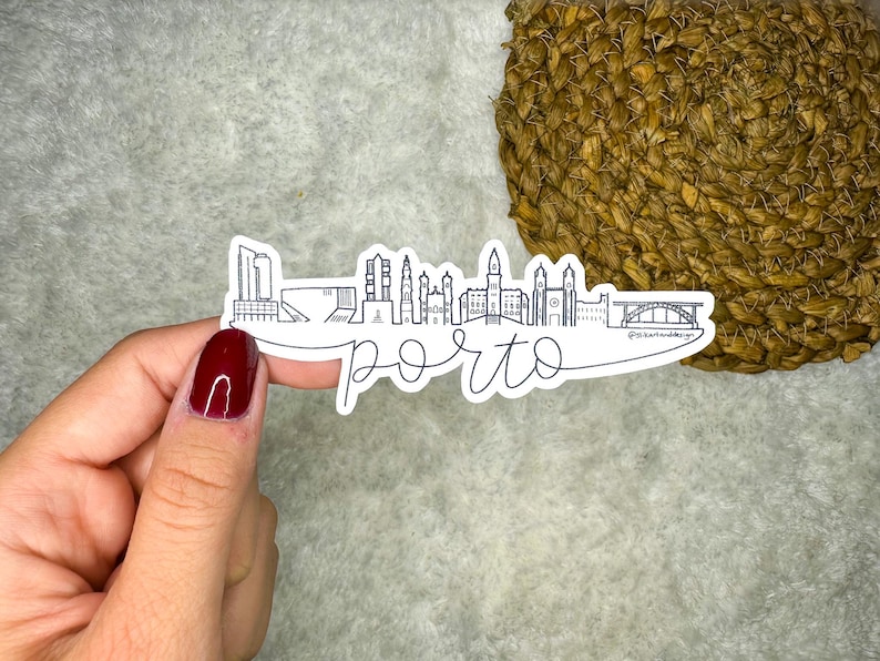 Puede incluir: Una pegatina blanca con un dibujo de l&iacute;nea negra del horizonte de Oporto, que incluye edificios y un puente. El texto "porto" est&aacute; escrito en una fuente cursiva debajo del horizonte.