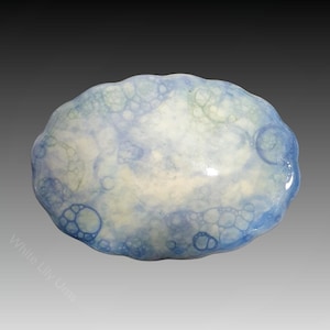 Puede incluir: Un plato de cerámica azul claro con un diseño de burbujas blancas y azules.