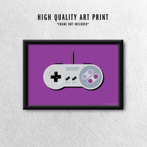 May include: A framed art print featuring a gray and purple video game controller on a purple background. The controller has a directional pad, buttons, and the text "SELECT" and "START". The print includes the text "HIGH QUALITY ART PRINT" and "*FRAME NOT INCLUDED*".