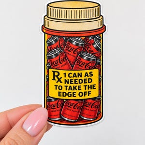 May include: A sticker shaped like a prescription pill bottle filled with black Coca-Cola Zero Sugar cans. The yellow label features the text Rx 1 CAN AS NEEDED TO TAKE THE EDGE OFF. The bottle has an orange cap and a white border, with a red and orange gradient.