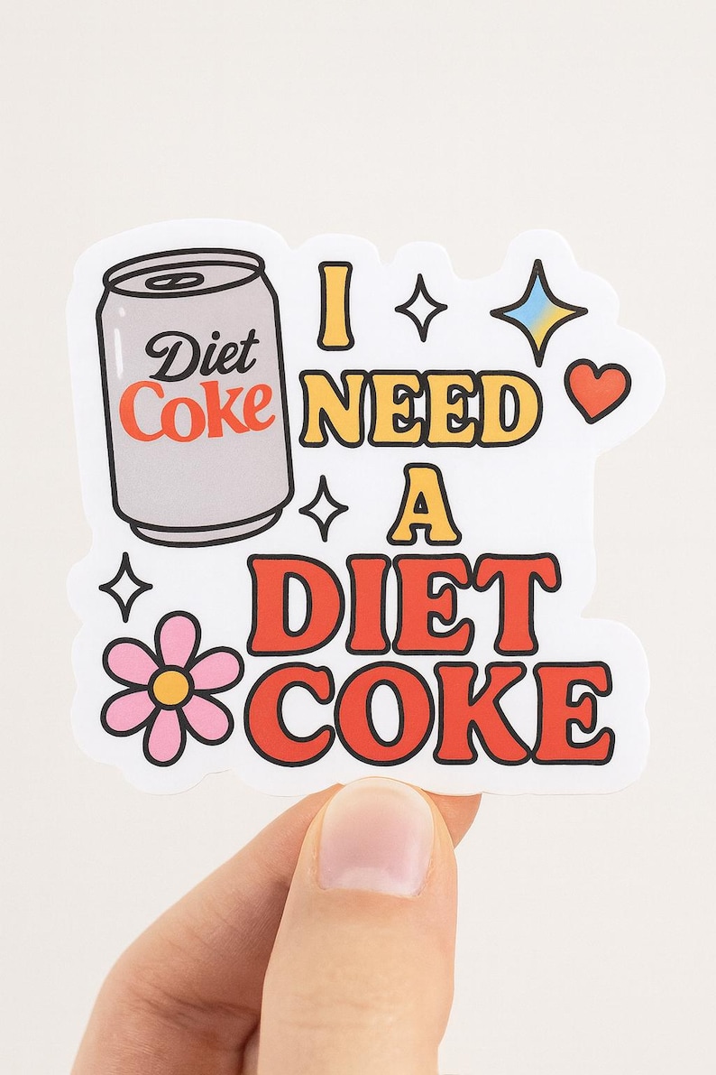 May include: A white sticker with the words "I NEED A DIET COKE" in a retro font. The sticker features a Diet Coke can graphic, stars, a heart, and a flower.