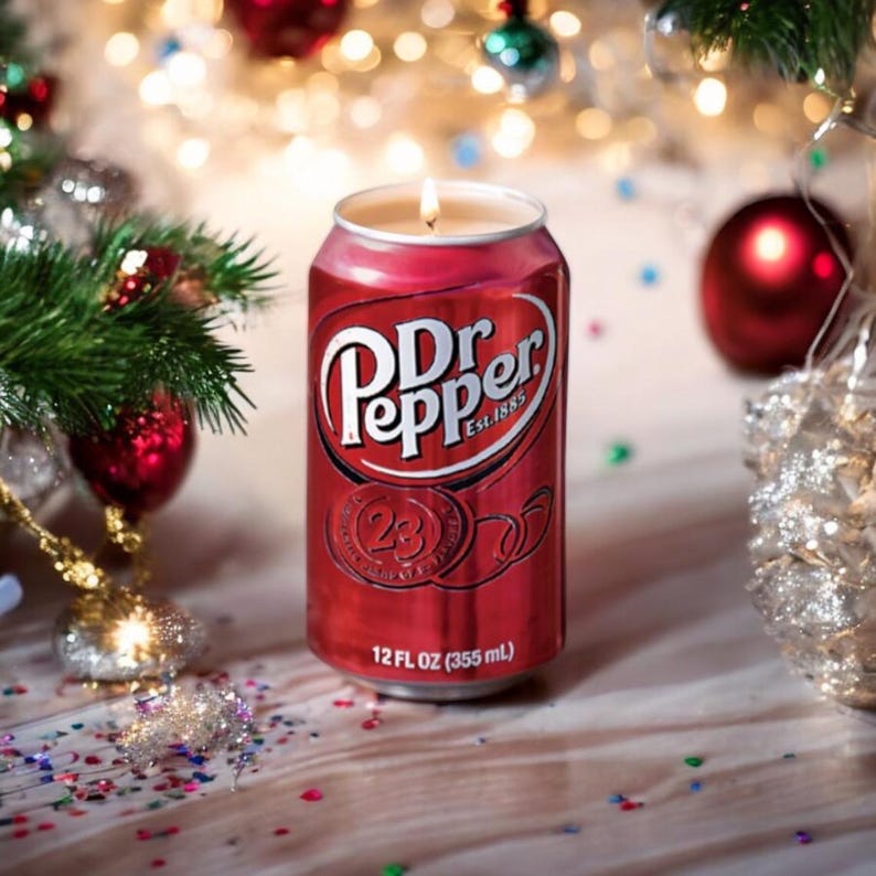 May include: A red and silver Dr Pepper can candle with a lit wick. The can is 12 fl oz (355 ml) and has the Dr Pepper logo and the text "Est. 1885".