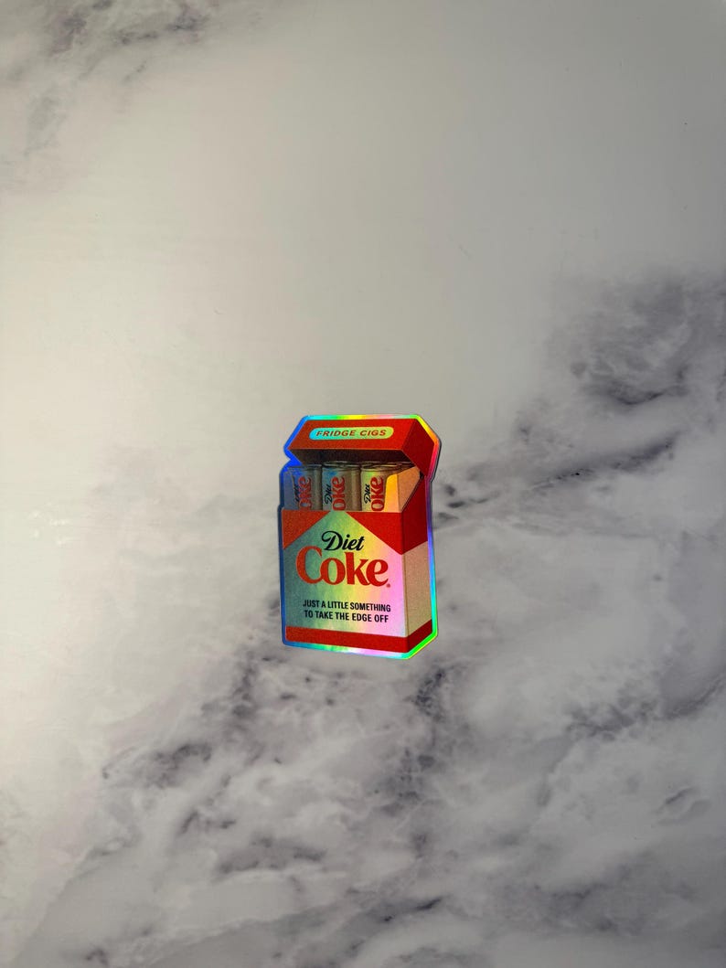 K&ouml;nnte beinhalten: Ein Aufkleber, der einer Diet Coke-Zigarettenschachtel &auml;hnelt. Die Schachtel ist rot und tr&auml;gt das Diet Coke-Logo und den Text "JUST A LITTLE SOMETHING TO TAKE THE EDGE OFF". Auf der Oberseite der Packung steht "FRIDGE CIGS".