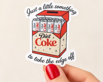May include: A die-cut sticker featuring a red and cream-colored cardboard box filled with silver Diet Coke cans. The text reads Just a little something to take the edge off and Diet Coke. The design includes small black star accents.