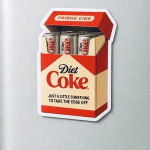 May include: A novelty sticker resembling a Diet Coke cigarette pack. The red and beige pack reads "Diet Coke" and "Just a little something to take the edge off." Inside are three Diet Coke cans. The top flap reads "FRIDGE CIGS."