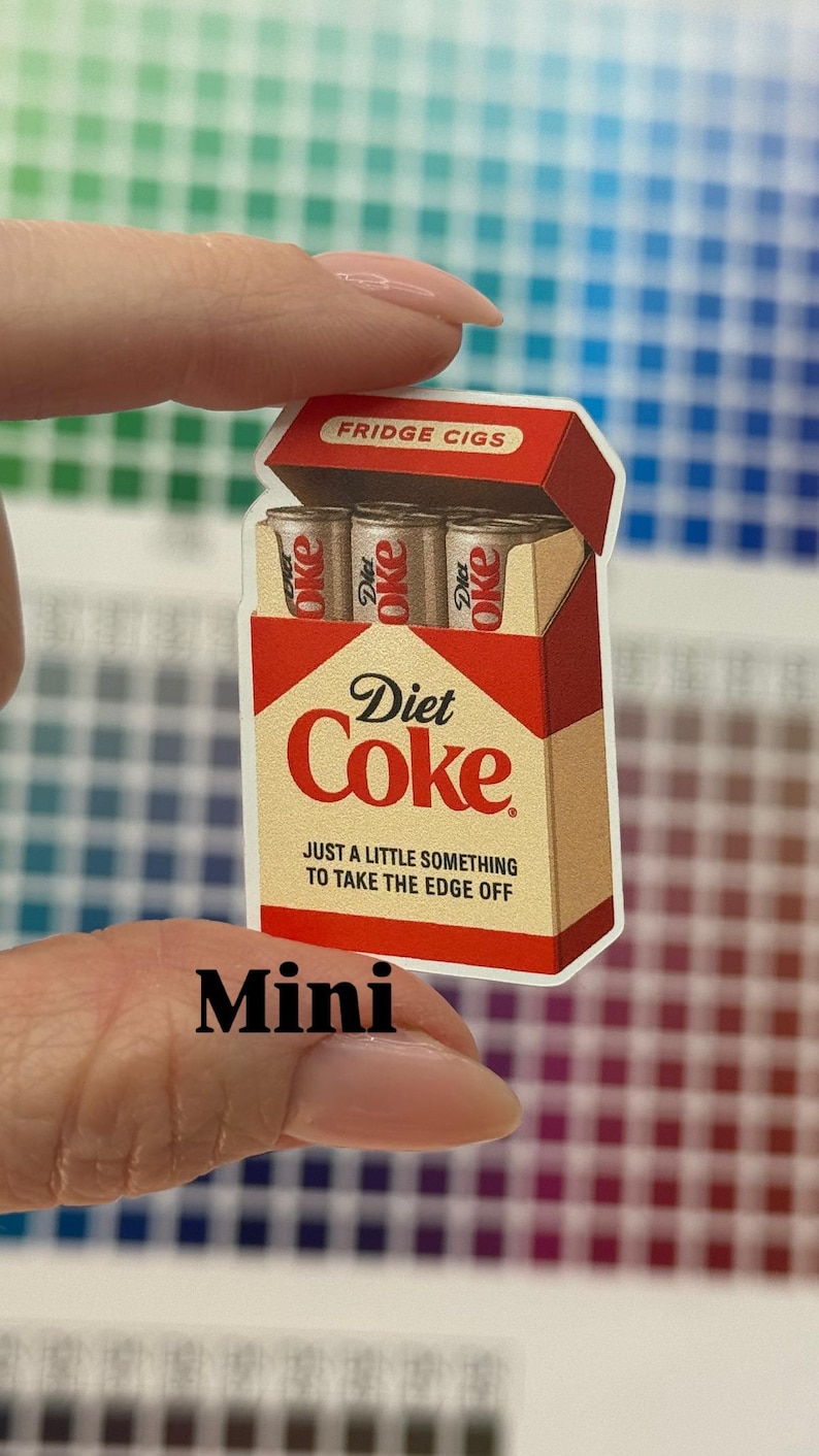 K&ouml;nnte beinhalten: Ein Aufkleber, der eine Packung "Fridge Cigs" mit drei "Diet Coke" Dosen zeigt. Die Verpackung ist rot und beige mit den Worten "Diet Coke" und "Just a little something to take the edge off". Das Wort "Mini" steht unten.
