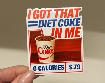May include: A rectangular sticker featuring the text I GOT THAT DIET COKE IN ME in red and blue. Below the text is an image of a Diet Coke cup with a red straw. The bottom section includes the text 0 CALORIES and $.79 in blue and red.