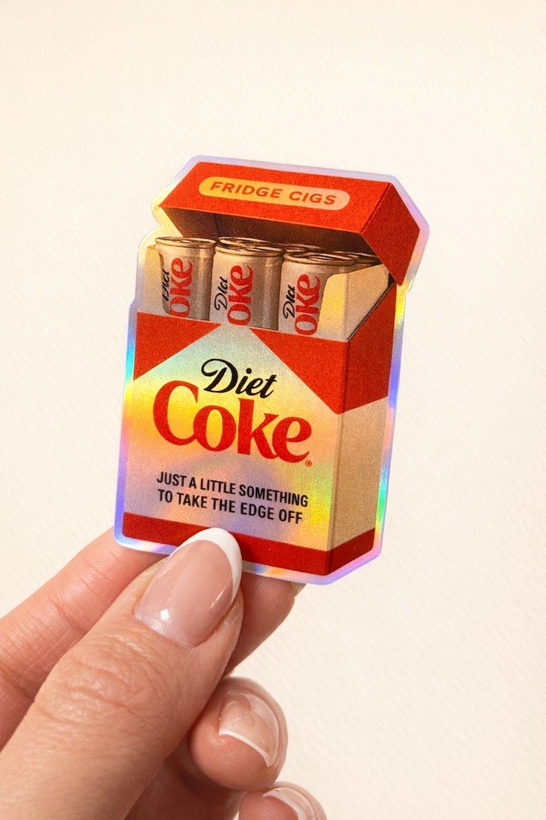 K&ouml;nnte beinhalten: Ein Aufkleber mit einer Diet Coke-Schachtel mit dem Text "FRIDGE CIGS". Die Schachtel enth&auml;lt drei Diet Coke-Dosen. Der Text "JUST A LITTLE SOMETHING TO TAKE THE EDGE OFF" ist ebenfalls sichtbar.