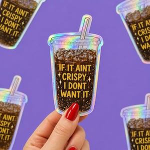 May include: A holographic sticker shaped like a clear plastic cup filled with dark brown soda, ice cubes, and a straw. The text IF IT AINT CRISPY I DONT WANT IT is printed in yellow on the cup, surrounded by small star icons and bubbles.