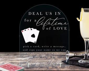 May include: Clear acrylic sign with the text "DEAL US IN for a lifetime of LOVE" and a graphic of playing cards. The sign also includes the text "pick a card, write a message, and sign your name so we can remember this day whenever we play a card game".