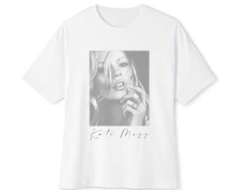 May include: White t-shirt featuring a black and white image of Kate Moss. The image is a close-up of her face and includes the name "Kate Moss" in a cursive font at the bottom of the image.
