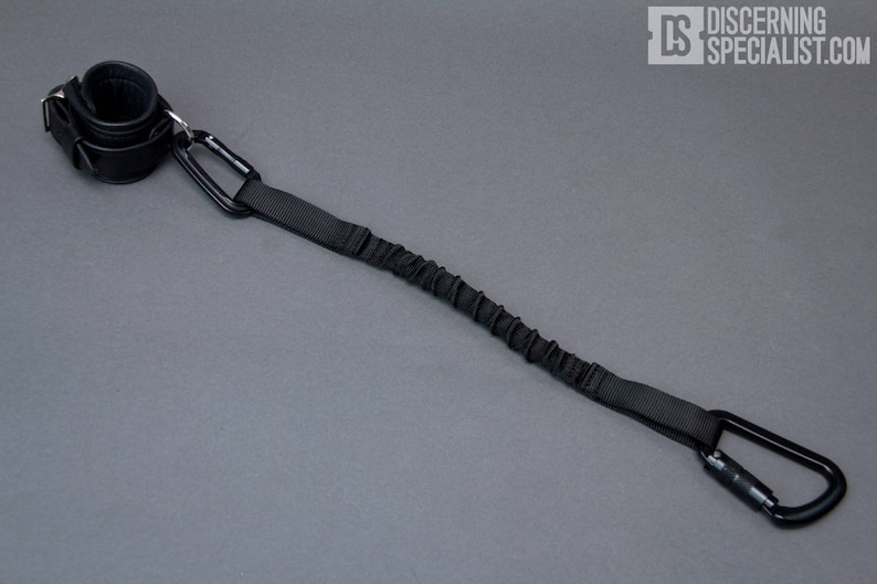 May include: A black elastic leash with a padded wrist strap and two metal carabiners.