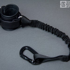 May include: Black leather wrist cuff with a black elastic strap and a black carabiner clip.