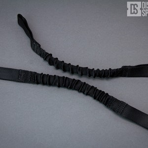 May include: Black bungee cord with two loops on each end. The cord is made of a stretchy material and is designed to be used for a variety of purposes.