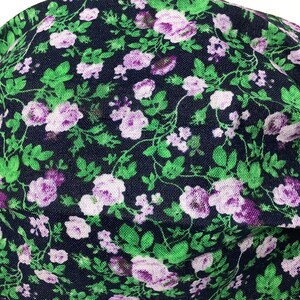 May include: A dark blue fabric face mask with a floral pattern featuring small purple and white flowers on green stems.