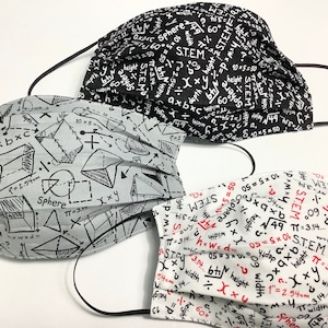 May include: Three fabric face masks with different patterns. The first mask is black with white mathematical equations and the word STEM. The second mask is gray with black mathematical equations and geometric shapes. The third mask is white with black mathematical equations and the word STEM in red.
