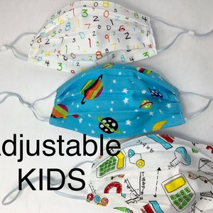 May include: Three adjustable face masks for kids. The first mask is white with colorful numbers printed on it. The second mask is blue with white stars and colorful planets printed on it. The third mask is white with colorful scientific illustrations printed on it. The masks have adjustable ear loops.