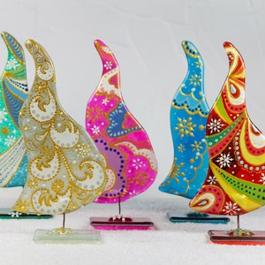 May include: Five hand-painted glass Christmas tree ornaments in various colors and patterns. The ornaments are shaped like a teardrop and have a gold metallic finish. The ornaments are on a white surface.