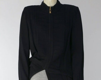 May include: A black long-sleeved jacket with a zipper closure and a high collar. The jacket has a slightly fitted silhouette and a textured fabric. The jacket is paired with a white and black striped skirt.
