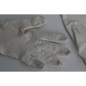 May include: A pair of white leather gloves. The gloves are made of a soft, supple leather and have a classic design.