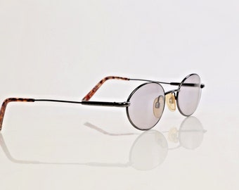 May include: A pair of round, black metal framed glasses with brown tortoise shell temple tips and gray tinted lenses.