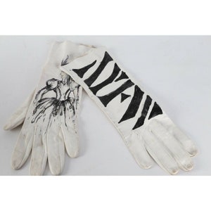 May include: A pair of white leather gloves with black ink drawings. One glove has a zebra stripe pattern and the other has a drawing of a woman in a dress.
