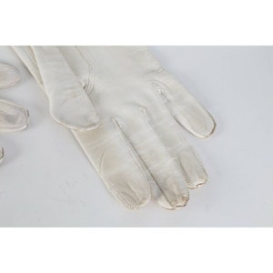 May include: A pair of white leather gloves. The gloves are made of a soft, supple leather and have a classic design.