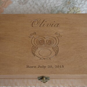 May include: A wooden keepsake box with an engraved owl design and the name "Olivia" and the date "Born July 28, 2015".