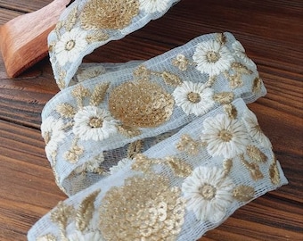 White lace with white flowers and gold sequins, embroidered with gold threads, beautiful and festive oriental style lace for decoration.