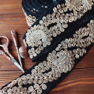 Può includere: Passamaneria in velluto nero con ricamo dorato e argentato. La passamaneria presenta un motivo paisley con paillettes.