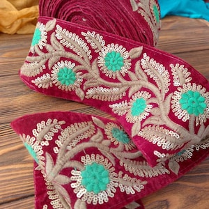 May include: Red velvet trim with gold and green embroidery. The trim features a floral design with sequins and beads.