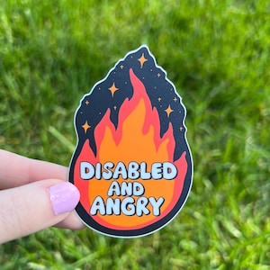 May include: A die-cut sticker featuring a stylized orange and red flame graphic against a black background with small white stars. The text "DISABLED AND ANGRY" is printed in bold, light blue, rounded capital letters across the center of the flame.