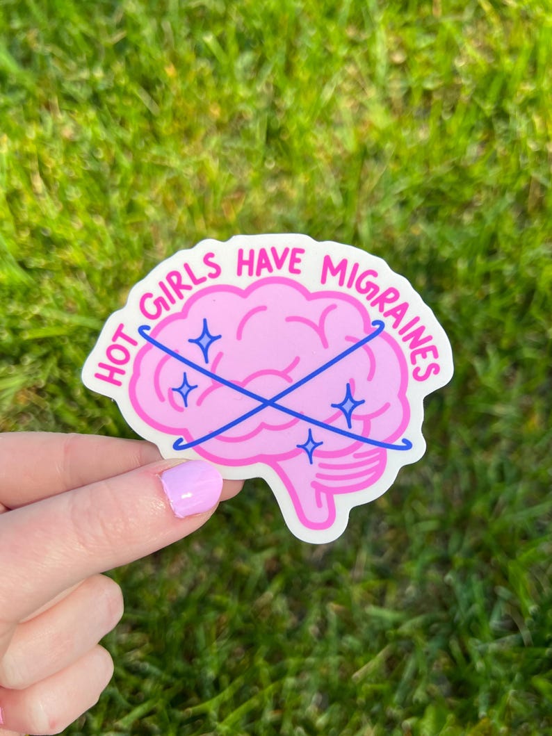 May include: A die-cut vinyl sticker featuring a pink brain illustration with the text HOT GIRLS HAVE MIGRAINES in hot pink lettering. Two crossed blue lines with small blue star accents overlay the brain, creating a graphic design on a white background.