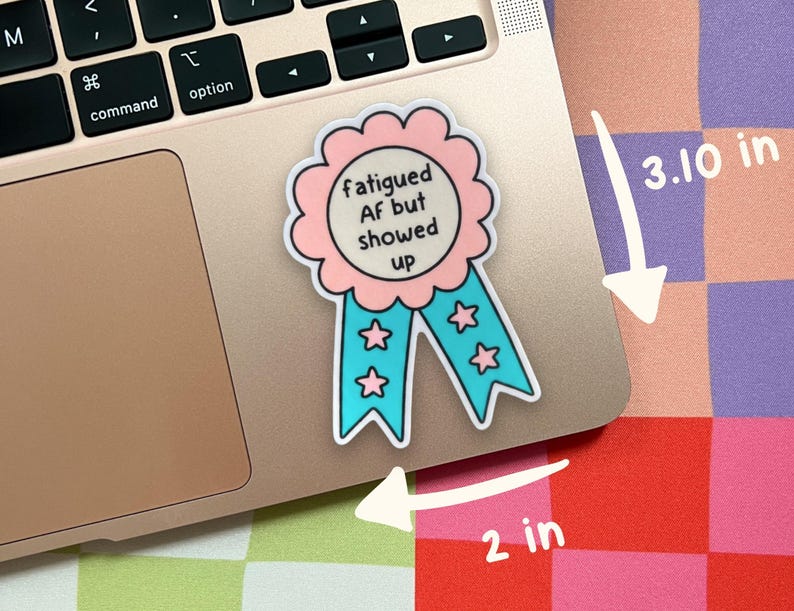 Pu&ograve; includere: Un adesivo a forma di nastro premio con un bordo smerlato rosa e code blu con stelle rosa. Il testo centrale recita "fatigued AF but showed up". L'adesivo misura 3,10 pollici di altezza e 2 pollici di larghezza, come indicato dalle frecce.