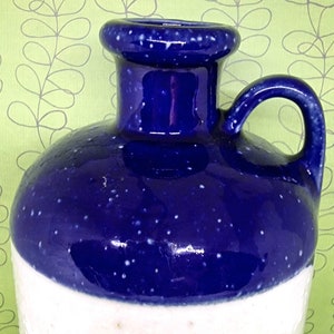 May include: A blue and white ceramic jug with a speckled glaze. The jug has a wide mouth and a handle.