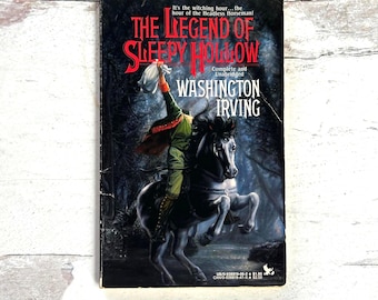 May include: A paperback book titled "The Legend of Sleepy Hollow" by Washington Irving. The cover features a headless horseman riding a black horse through a dark forest. The title is in red and the author's name is in white.