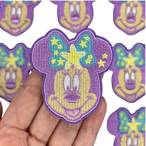May include: Purple and yellow embroidered iron-on patch of a cartoon mouse with a bow and stars.