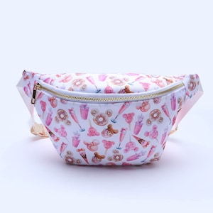 Könnte beinhalten: Weiße Bauchtasche mit goldenem Reißverschluss und einem rosa-weißen Muster aus Donuts, Eiswaffeln und Mickey-Maus-Köpfen.