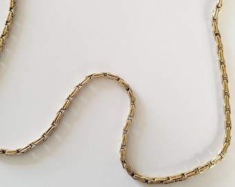 May include: A gold chain necklace with a box chain design. The chain is about 18 inches long.