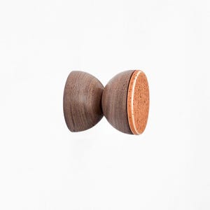 Può includere: Un pomello in legno con finitura marrone e un accento marrone chiaro. Il pomello ha la forma di una clessidra arrotondata.