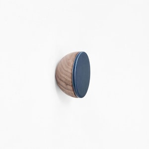 May include: A wooden wall hook with a dark blue circular top. The hook is made of natural wood and has a rounded shape.