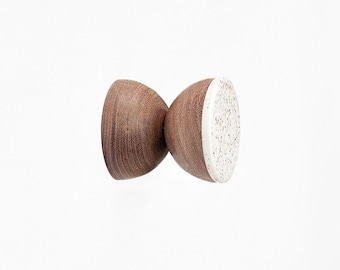 May include: A wooden wall hook with a white speckled ceramic top. The hook is brown and has a natural wood grain.