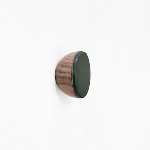 May include: A wooden wall hook with a dark green rubberized surface. The hook is designed to hold items securely.
